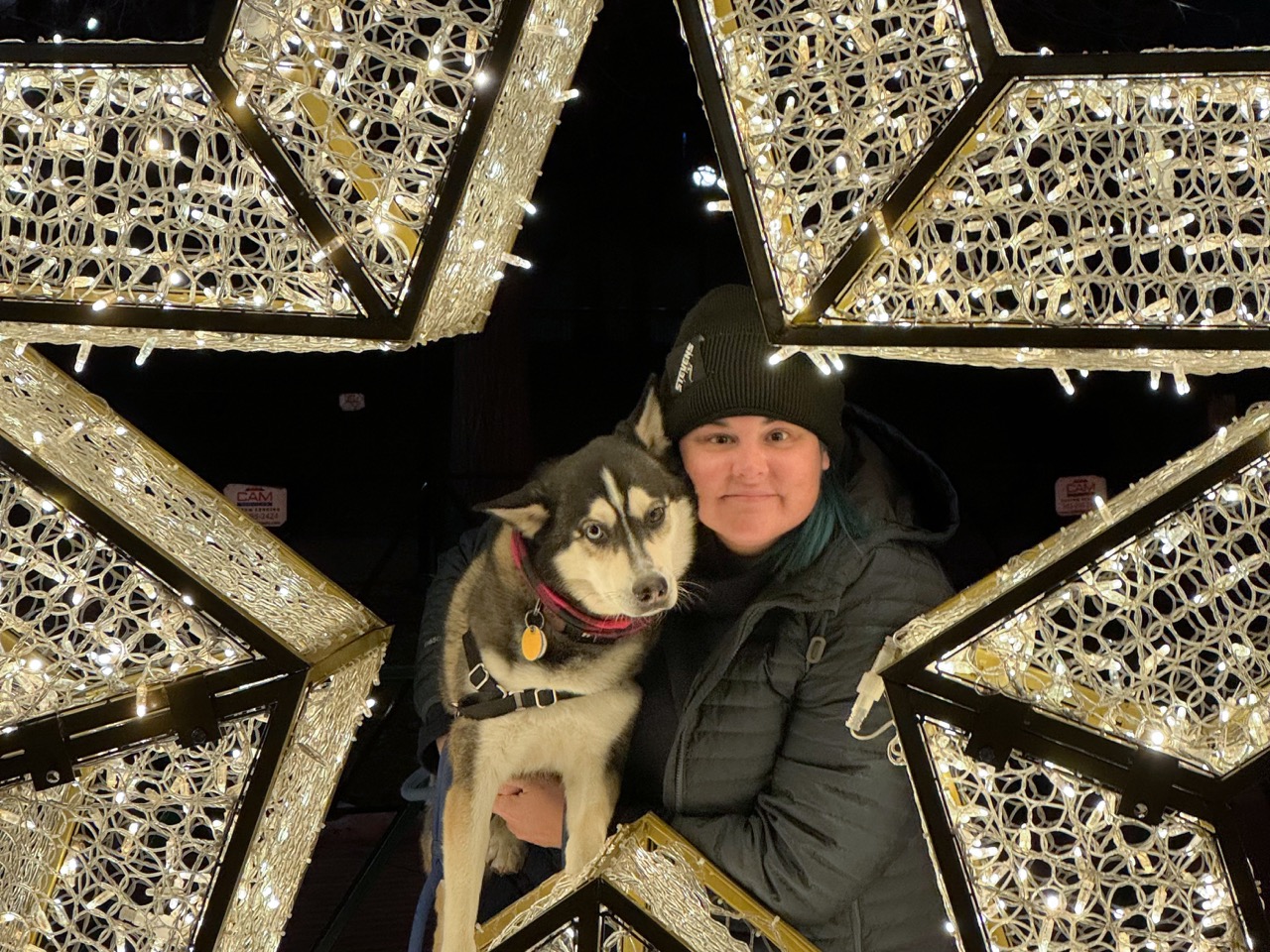 Woman and dog smiling in the middle of a light up holiday star